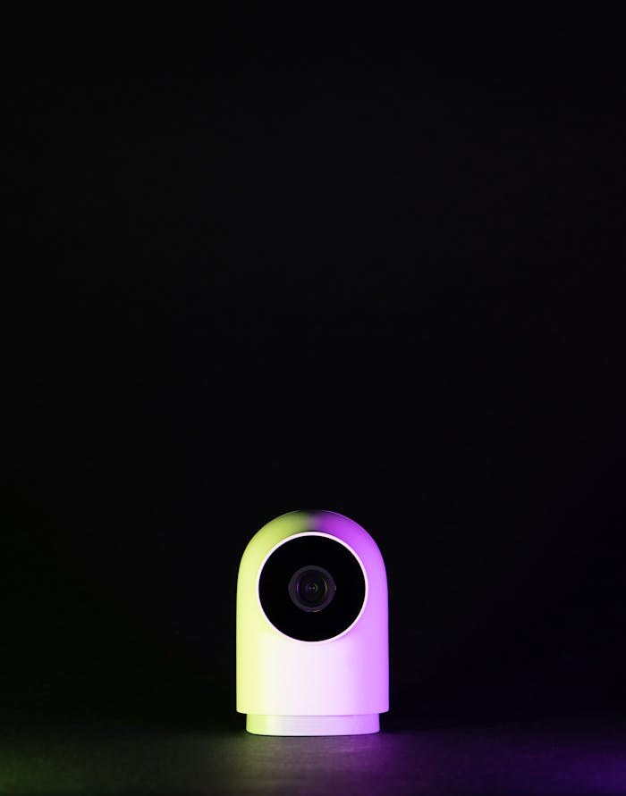 Sleek white webcam on a black background with neon lighting, emphasizing technology and modern design.